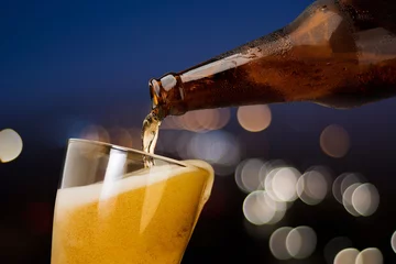 Crédence de cuisine en verre imprimé Bière Mouvement de la bière qui coule de la bouteille dans le verre sur fond de nuit lumineuse bokeh boire de l& 39 alcool célébration concept design