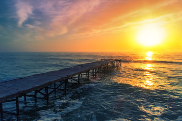 Aerial view over the old broken bridge in the sea, sunrise shot.