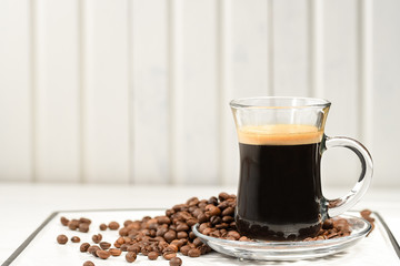 Espresso. Glass espresso cup with coffee beans on a light background