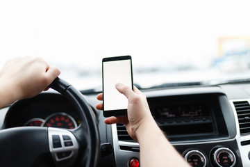 Close-up of male driver hands using mobile phone in luxury car.