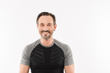 Portrait of happy caucasian man 30s wearing sportswear posing on camera with smile and satisfied look after fitness or practising, isolated over white background