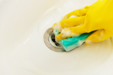 Cleaning Bathroom Sink with Detergent in Yellow Rubber Gloves with Blue Sponge - Housework, Spring Cleaning Concept.
