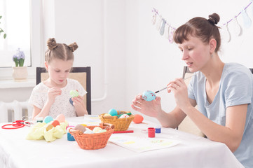 Obraz na płótnie Canvas Religious holidays: Mom and daughter paint Easter eggs.