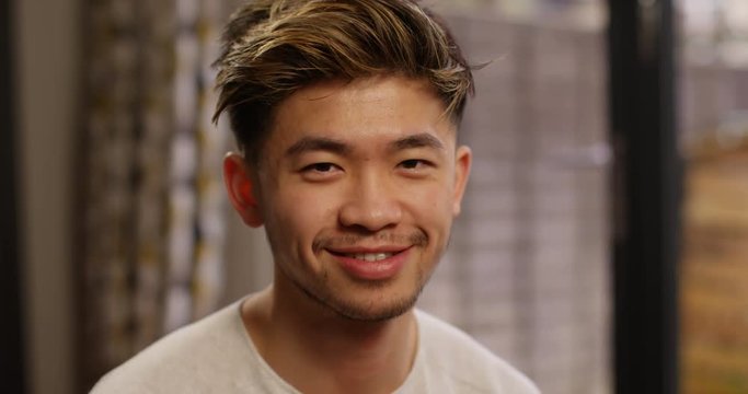 4K Close up portrait of happy young Asian man winking & smiling at camera