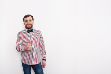 Fototapeta premium Young caucasian bearded man showing thumb up sign. In studio with white background and copyspace