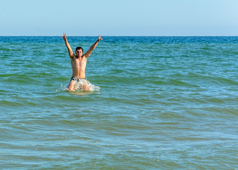 Fototapeta na wymiar A sports man jumping over the sea waves in the black sea