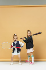 Portrait of two girls as tennis players holding tennis racket. Studio shot.