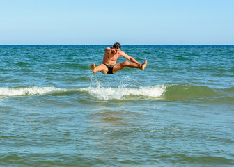 A sports man jumping over the sea waves in the black sea