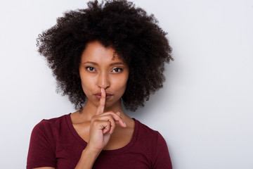 Close up beautiful young black woman with finger over lips gesturing silence