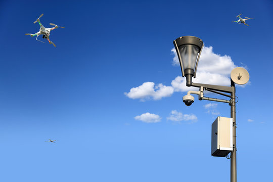 Monitoring, drony, kamera i oświetlenie na tle błękitnego nieba.