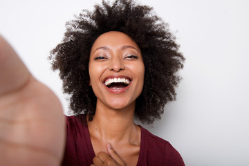 young black woman taking selfie and laughing against white background