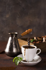 Cup of coffee with cooffee beans, wooden box with grains of coffee and spices, cezve on a stone background