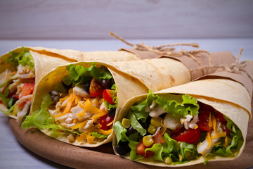 Chicken wraps. Tortilla, burritos, sandwiches twisted rolls on wooden table
