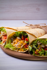 Chicken wraps. Tortilla, burritos, sandwiches twisted rolls on wooden table