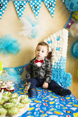 A cute little boy in a suit sitting on a table