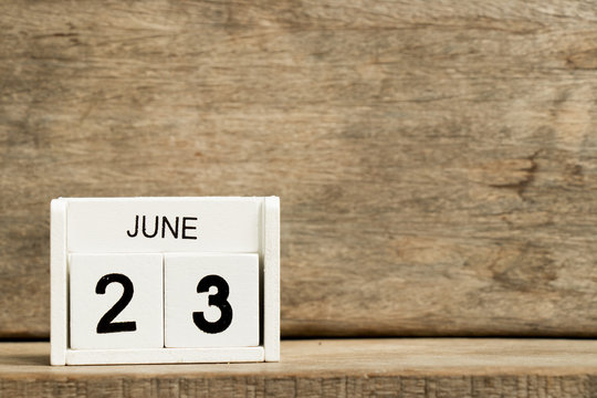 White block calendar present date 23 and month June on wood background