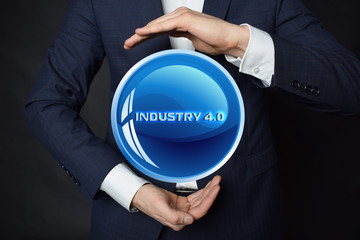 In the hands of a businessman, a neon circle with the inscription:INDUSTRY 4.0