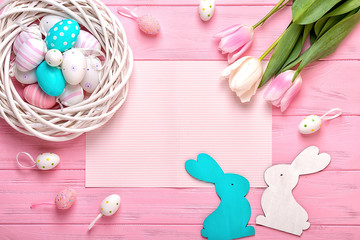 Easter eggs in a wicker basket and a bouquet of tulips on a pink background. Holiday greeting card for Easter!	