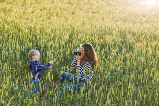 Young Woman Taking Pictures Of A Child In A Field