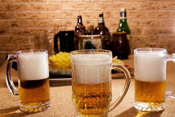 Glasses of beer and plates of appetizers are on the table.