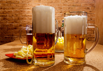 Glasses of beer and plates of appetizers are on the table.