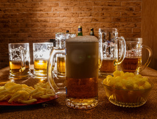 Glasses of beer and plates of appetizers are on the table.