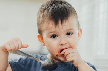 little baby boy in the kitchen eating pasta with cutlets, very tasty