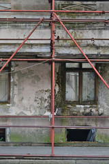 Red scaffolding surrounding the old, destroyed building