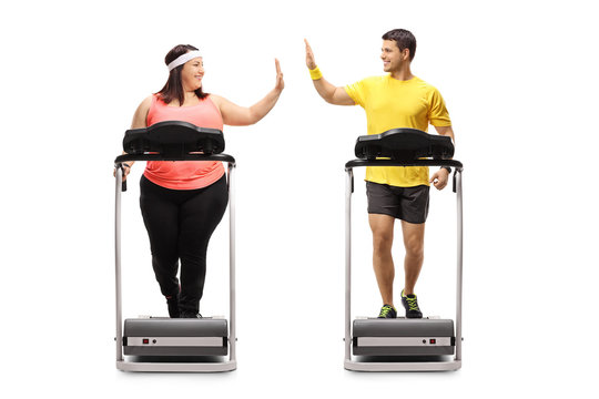 Overweight woman and a young man exercising on treadmills and high-fiving each other
