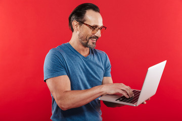 Happy emotional positive man using laptop computer.