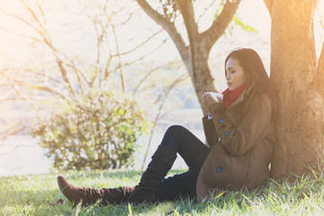 Woman sitting holding a coffee cup sitting under a tree