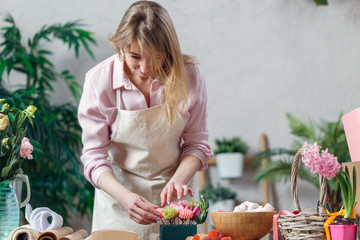 Photo of blonde florist making composition of flowers