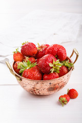Strawberries in small vintage copper colander. Freshly picked strawberries from the garden.