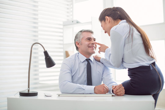 Relationships at work. Nice positive attractive woman looking at her boss and flirting with him while expecting a promotion