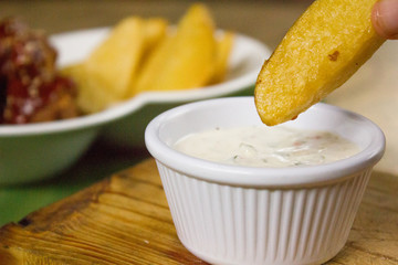 Detalle de papas rústicas fritas con salsa tártara