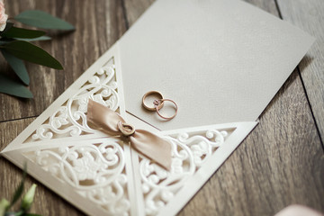 wedding rings lie on the invitation card on background of a bouquet