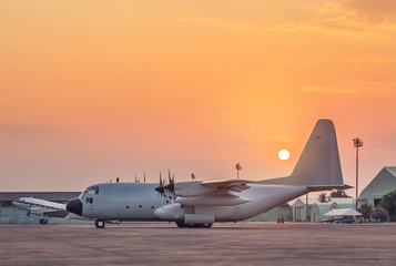 Fototapeta na wymiar Transport military cargo aircraft parked standby ready to takeoff for military mission on runway in the base airforce on sunset