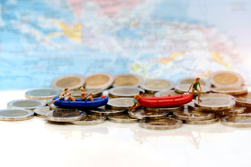 Miniature people, Children with paddle boat on coins. Concept of travel busines.