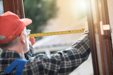Repairman taking measures with tape measure, light effect