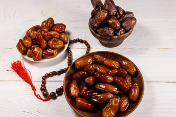Dates fruit and rosary on white wooden table