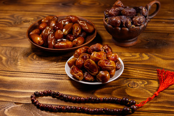 Dates fruit and rosary on wooden table