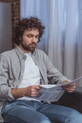 handsome man reading business newspaper in living room