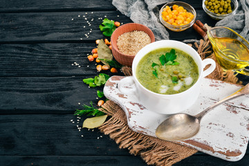 Soup with broccoli and peas and vegetables in a bowl. Healthy food. On a black wooden background. Top view. Copy space for your text.