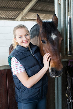 Portrait Of Female Owner In Stable With Horse