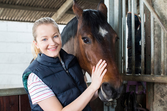 Portrait Of Female Owner In Stable With Horse