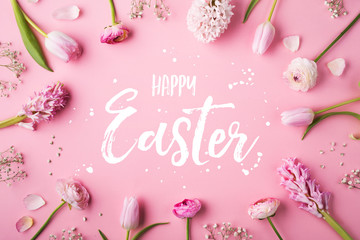 Happy Easter phrase and spring flat lay on a pink bacground.