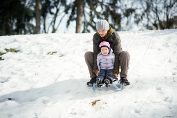 Fototapeta na wymiar Man and little girl play on the sledge in winter park