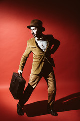 man posing in studio with suitcase in hands
