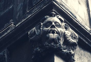 Gargoyle with protruding tongue. Architectural detail of old house in medieval town of  Arles....