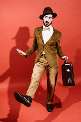 man posing in studio with suitcase in hands